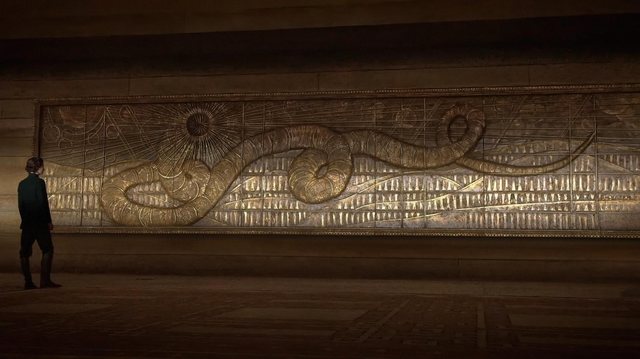 Shai-Hulud worked in gold across a paneled wall, Paul Atreides small beneath it, a still from Dune